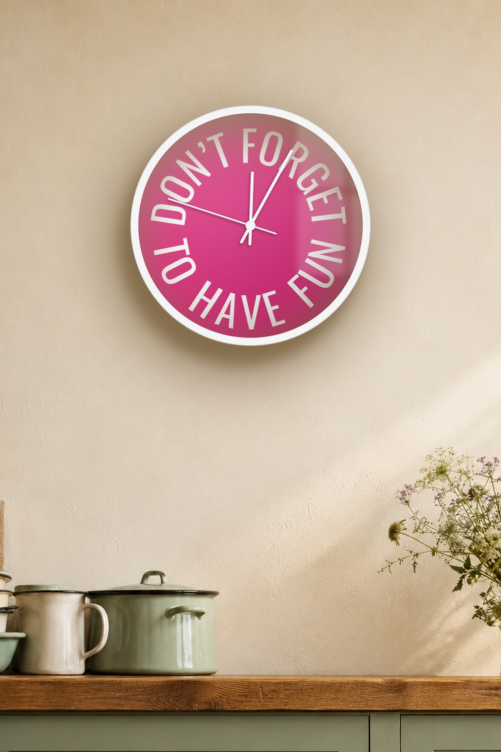 "Don't forget to have fun" wall clock in pink and white, on a wall
