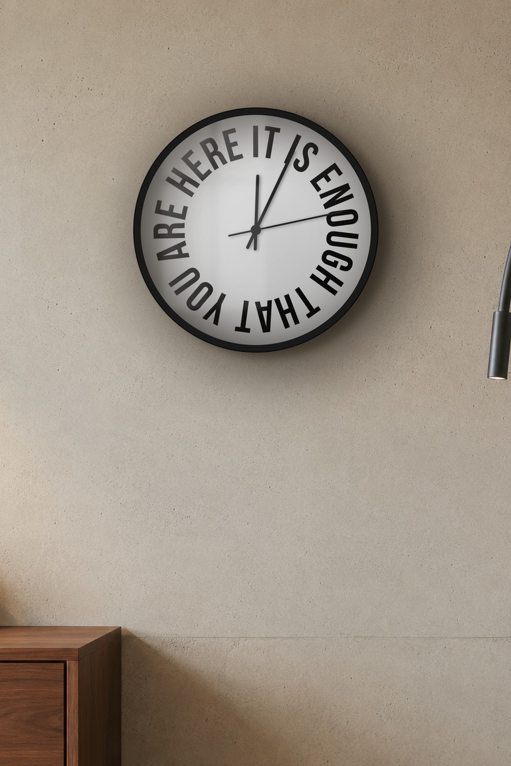 "It is enough that you are here" wall clock in light neutral and black, on a wall