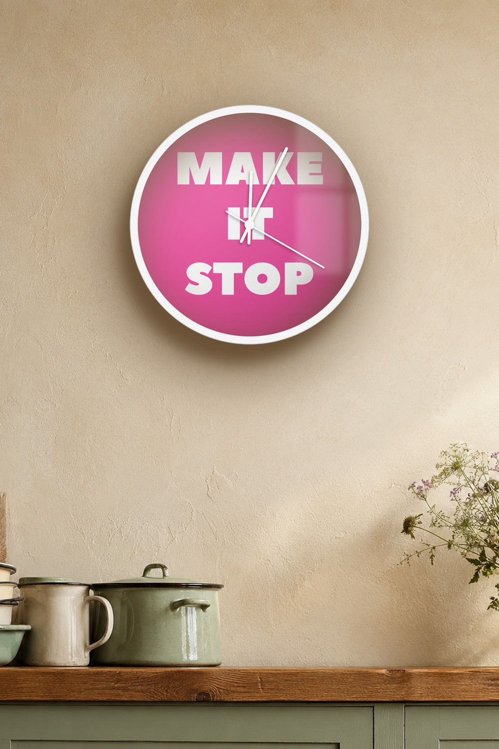 "Make it stop" wall clock in pink and white, on a wall