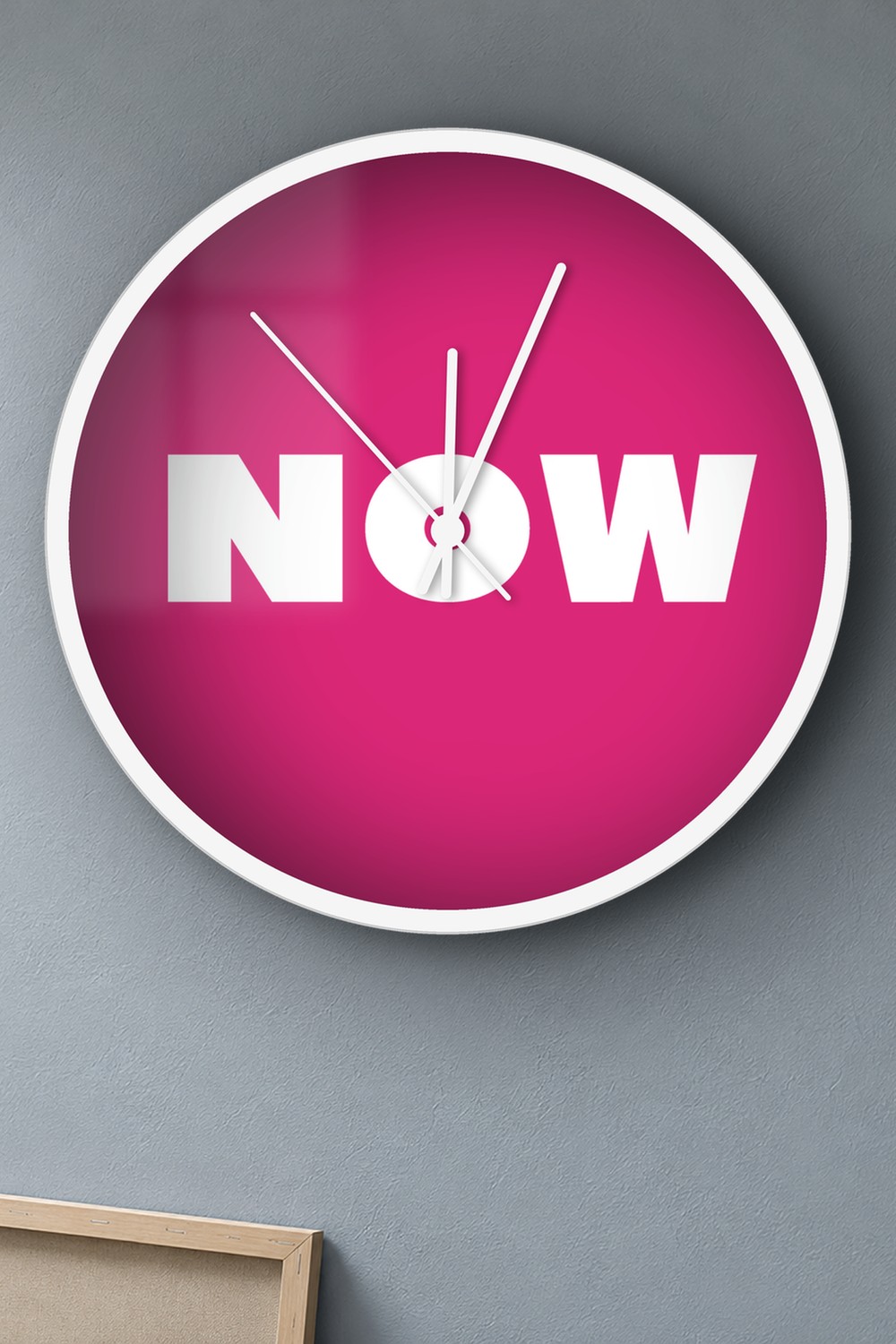 "now" wall clock in pink and white, on a wall