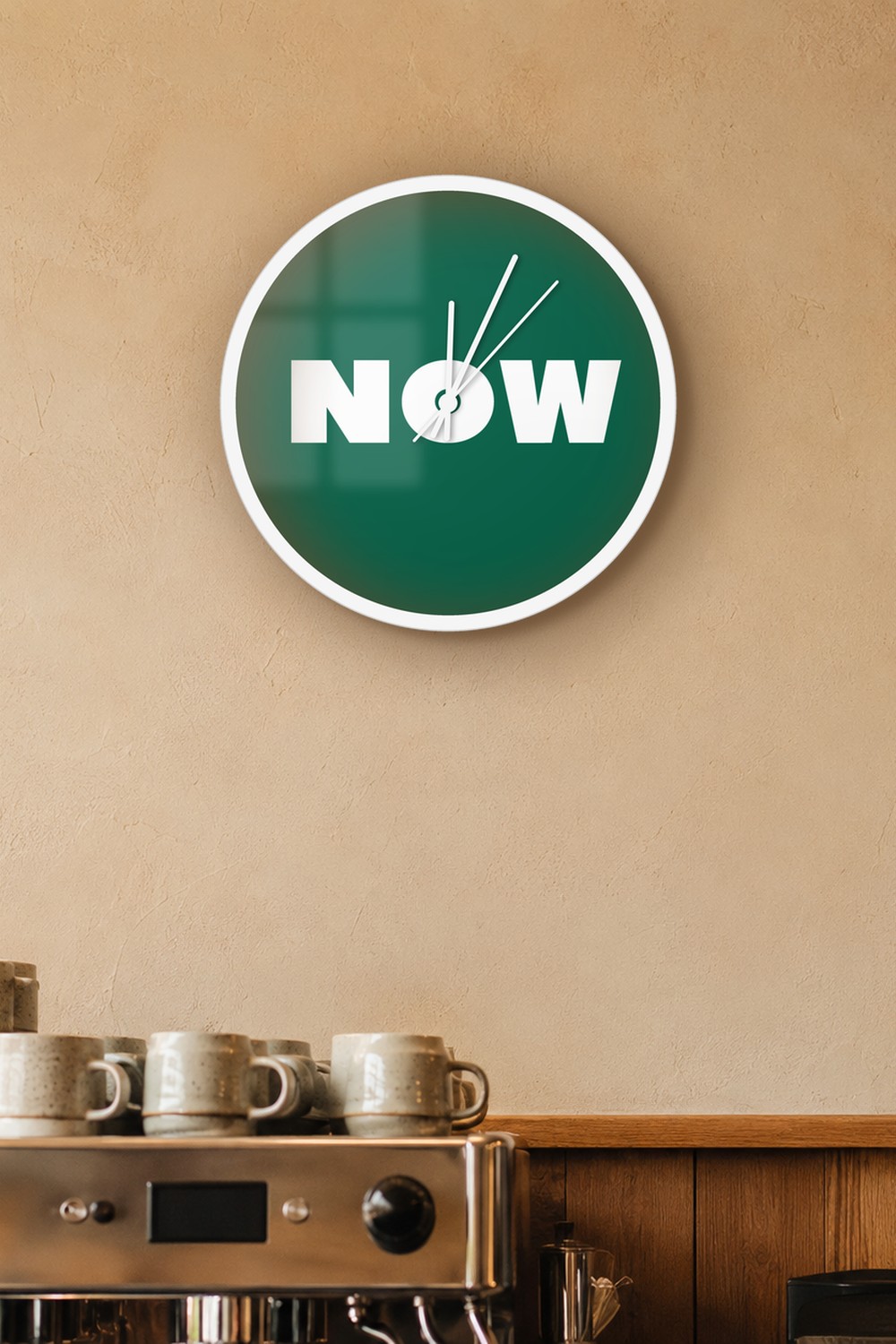 "now" wall clock in dark emerald and white, on a wall