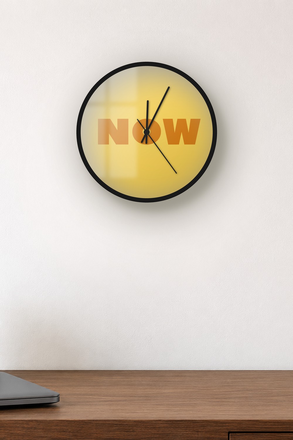 "now" wall clock in light amber and amber, on a wall